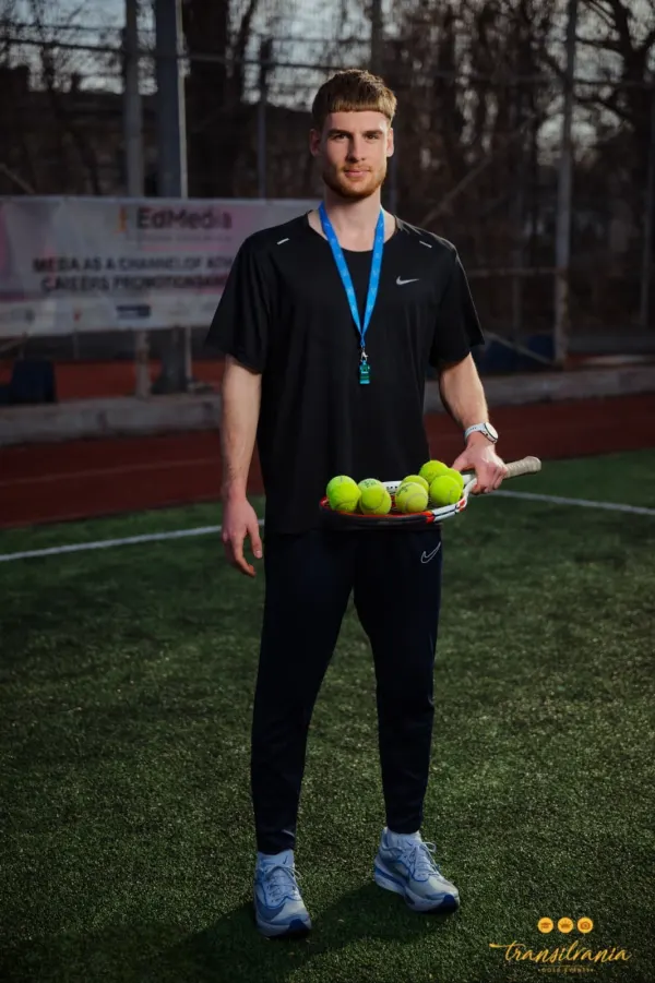 Antrenor ținând o rachetă cu mingi de tenis